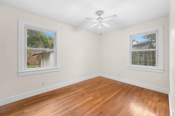 a view of an empty room with wooden floor and a window