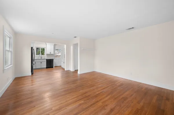 a view of empty room with kitchen and window