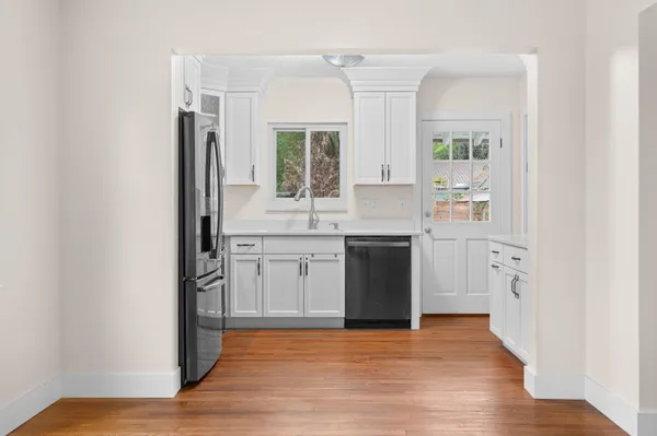 a view of a kitchen with a sink and dishwasher with wooden floor