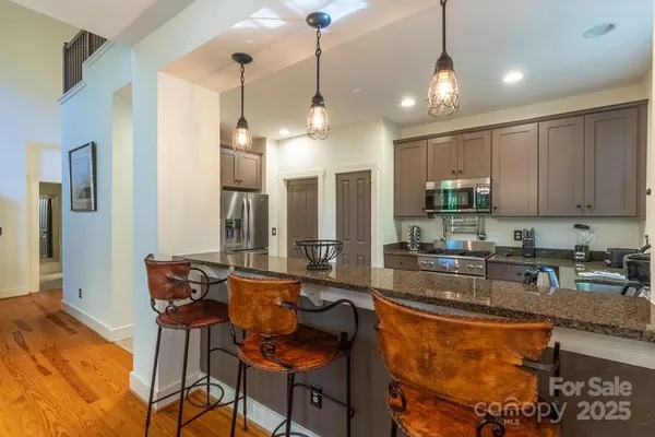 a kitchen with stainless steel appliances granite countertop a stove a refrigerator a sink dishwasher a dining table and chairs with wooden floor