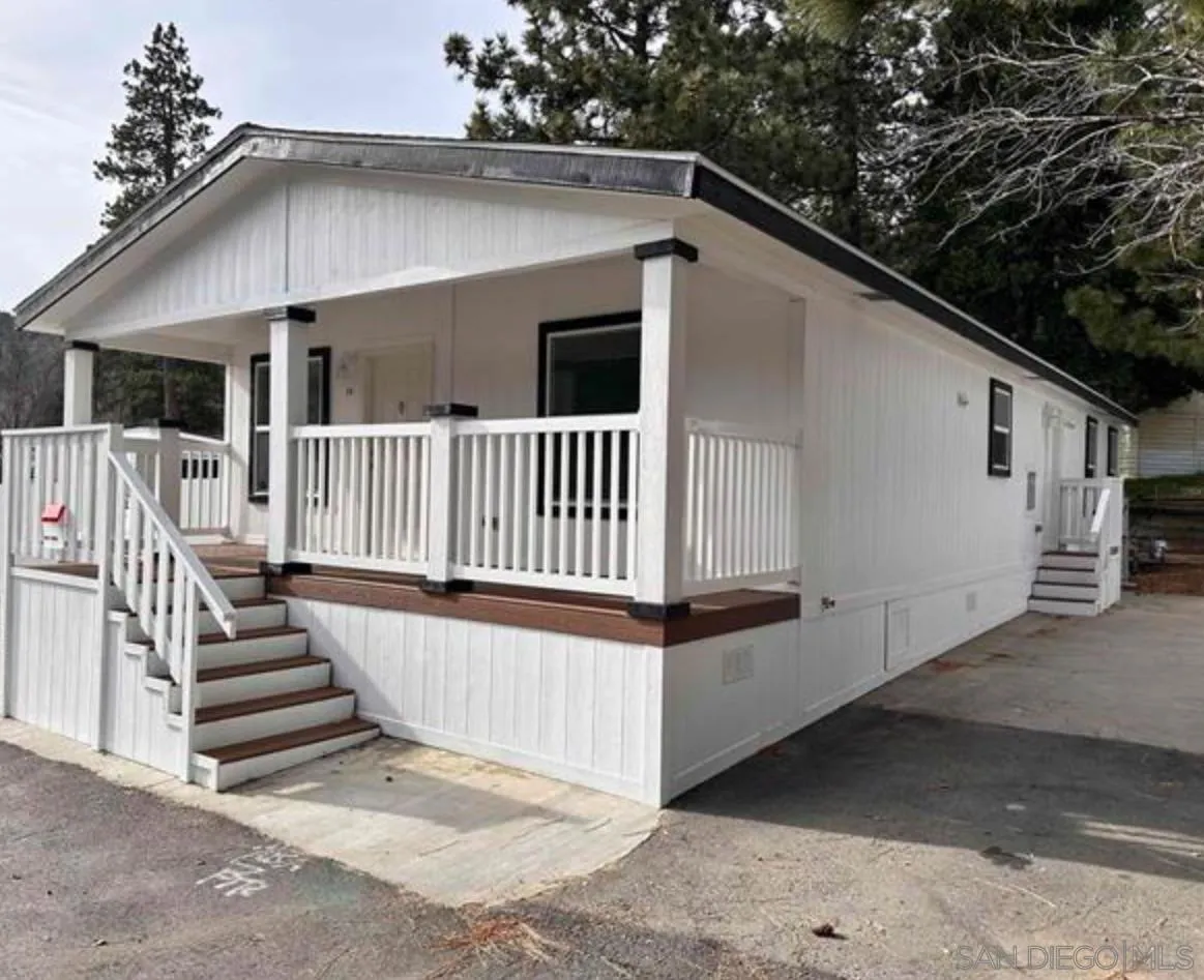 22899 Byron Road, Unit 29 Crestline, CA 92325 - Photo 3 of 8 a view of a white house with a small yard and wooden fence