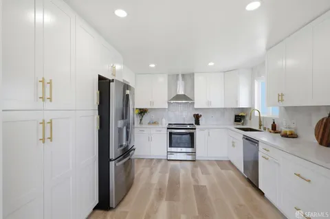 a kitchen with white cabinets and stainless steel appliances