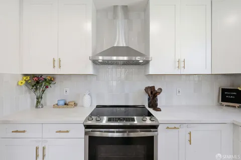 a kitchen with a stove and white cabinets