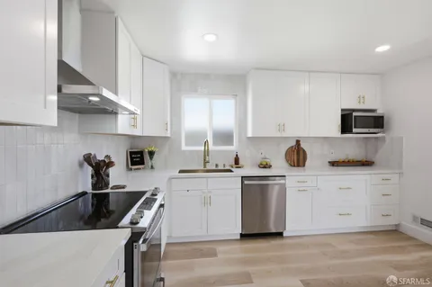 a kitchen with stainless steel appliances a sink a stove a microwave a refrigerator a counter top space and cabinets