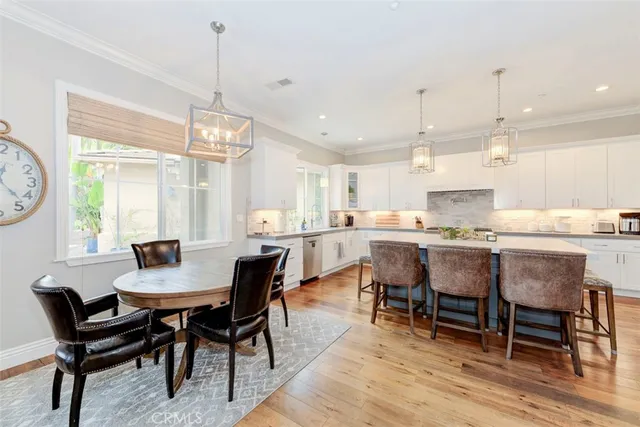 a dining room with stainless steel appliances kitchen island granite countertop a dining table chairs and a refrigerator