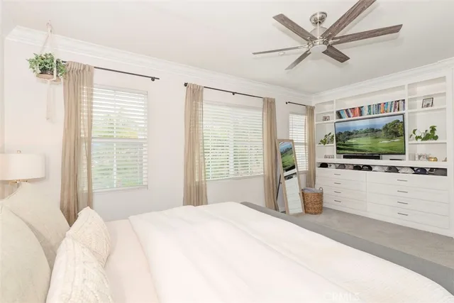 a bedroom with a large bed a flat screen tv and a chandelier