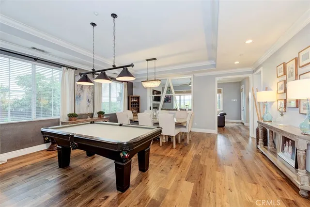 a room with wooden floor pool table and windows