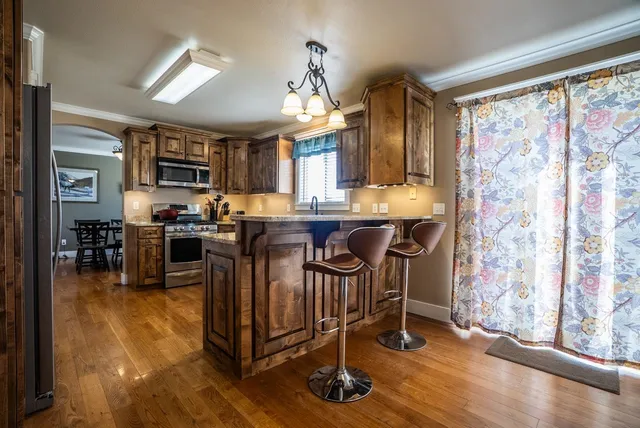 a kitchen with stainless steel appliances granite countertop a stove top oven a sink a dining table and chairs