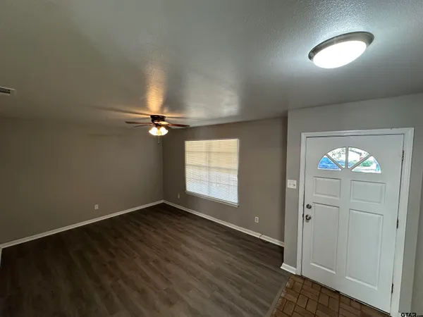 an empty room with wooden floor and windows