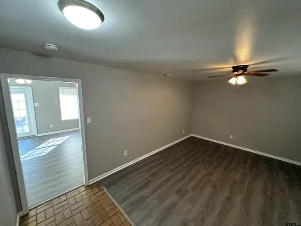 an empty room with wooden floor mirror and windows
