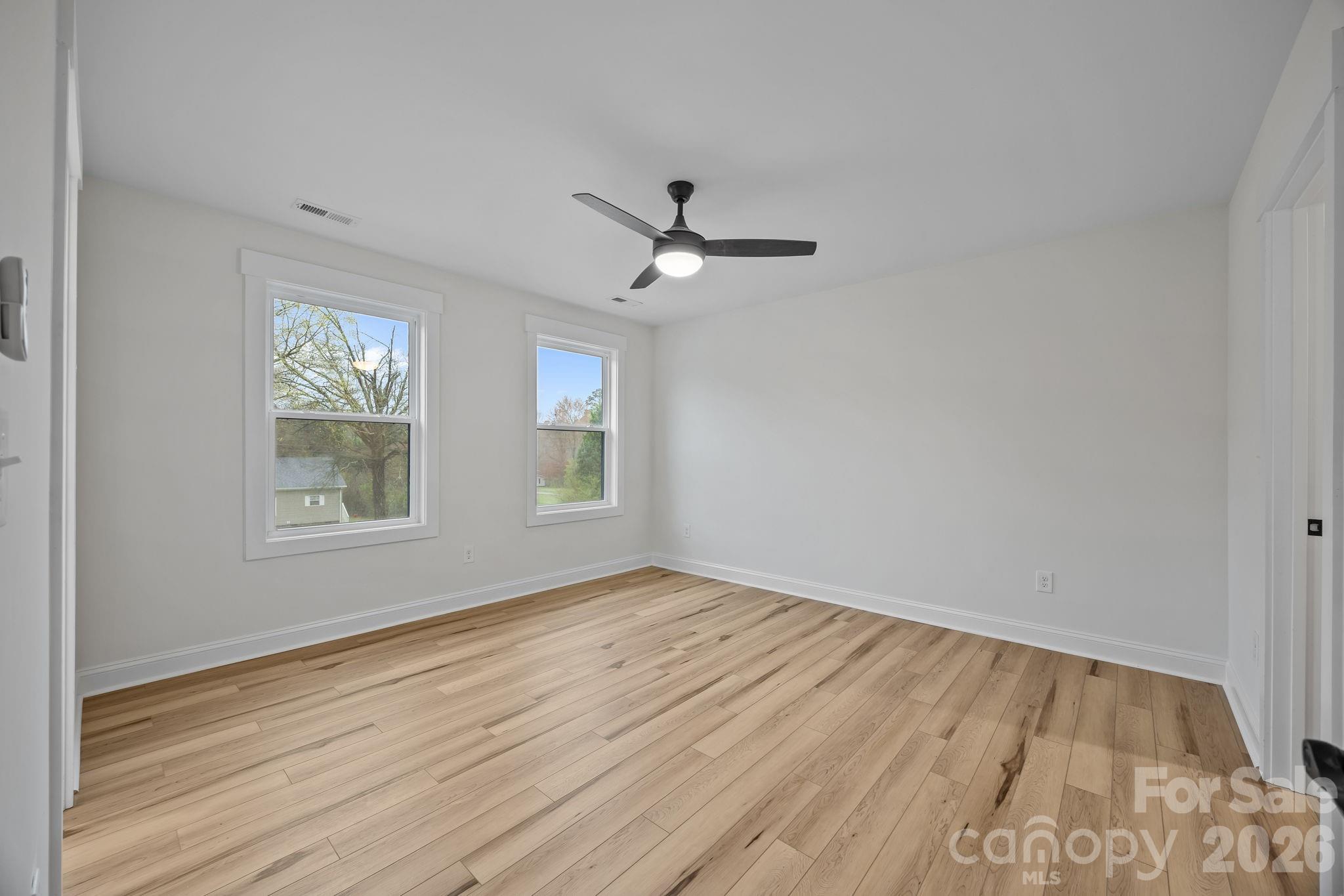 1030 Gibson Road Salisbury, NC 28147 - Photo 39 of 47 an empty room with wooden floor ceiling fan and windows