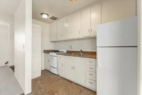 a kitchen with white cabinets and white appliances