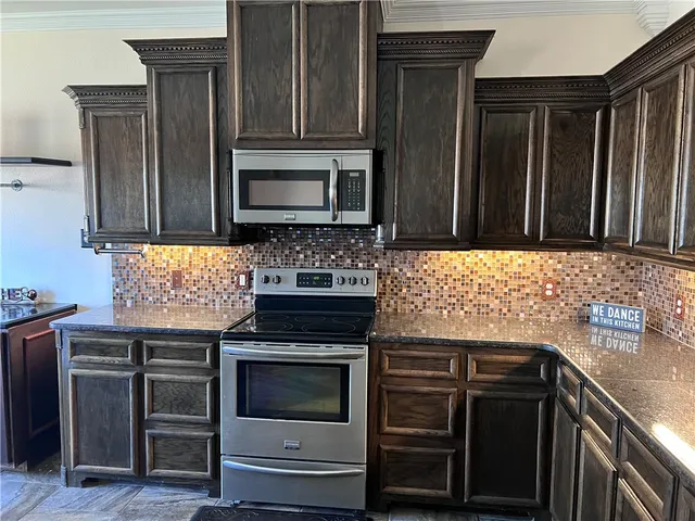 a kitchen with stainless steel appliances granite countertop wooden cabinets and stove