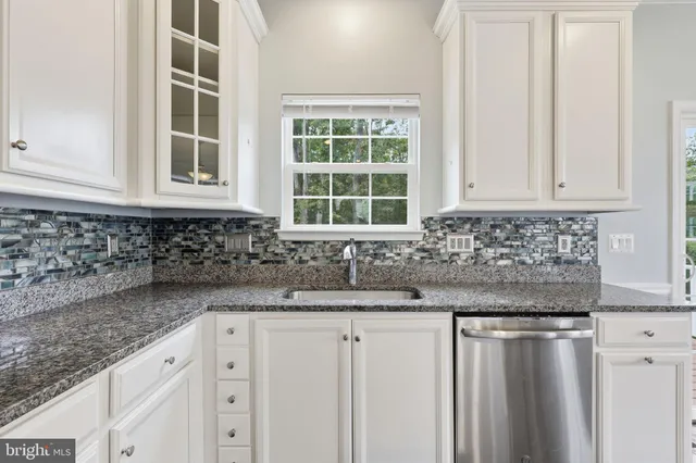 a kitchen with granite countertop white cabinets and window
