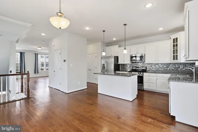 a large kitchen with white cabinets stainless steel appliances a dining table and chairs
