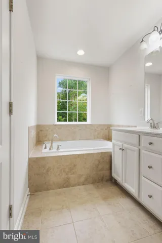 a spacious bathroom with a tub sink and mirror