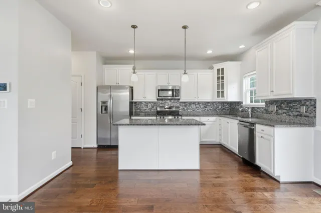 a kitchen with stainless steel appliances granite countertop a refrigerator a sink a stove and oven