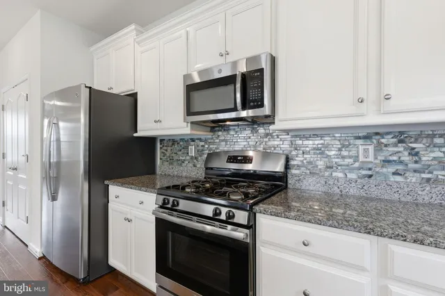 a kitchen with stainless steel appliances white cabinets and a stove a oven with wooden floor