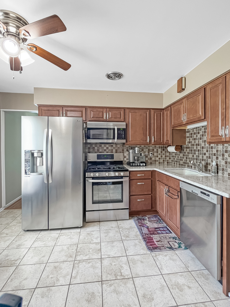 985 Greenridge Road Buffalo Grove, IL 60089 - Photo 4 of 20 a kitchen with stainless steel appliances granite countertop a refrigerator and a stove top oven