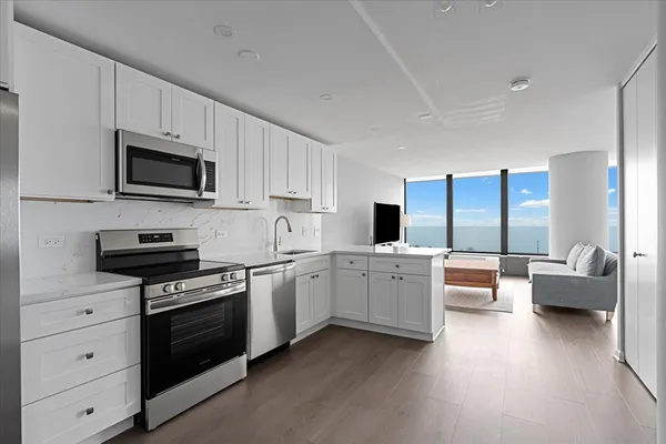 a kitchen with granite countertop a stove top oven a sink dishwasher a dining table and chairs with wooden floor