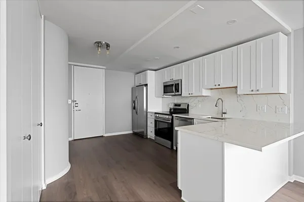 a kitchen with cabinets appliances wooden floor and a window