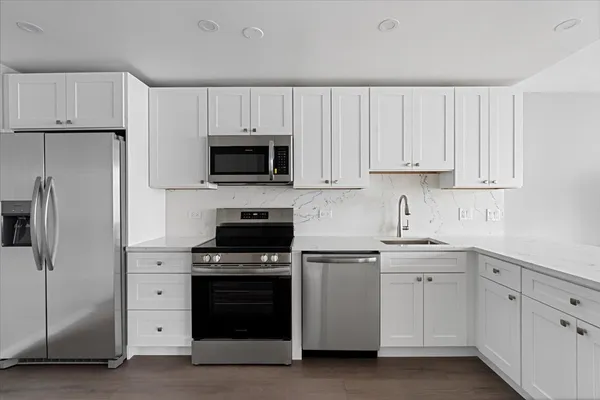 a kitchen with white cabinets and stainless steel appliances