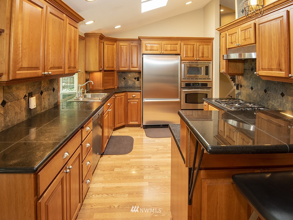21922 Southeast 255th Place Maple Valley, WA 98038 - Photo 3 of 40 a kitchen with stainless steel appliances granite countertop a sink a stove and a refrigerator