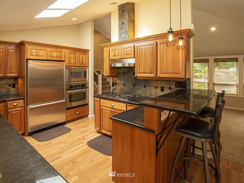 21922 Southeast 255th Place Maple Valley, WA 98038 - Photo 4 of 40 a kitchen with granite countertop a sink and a refrigerator