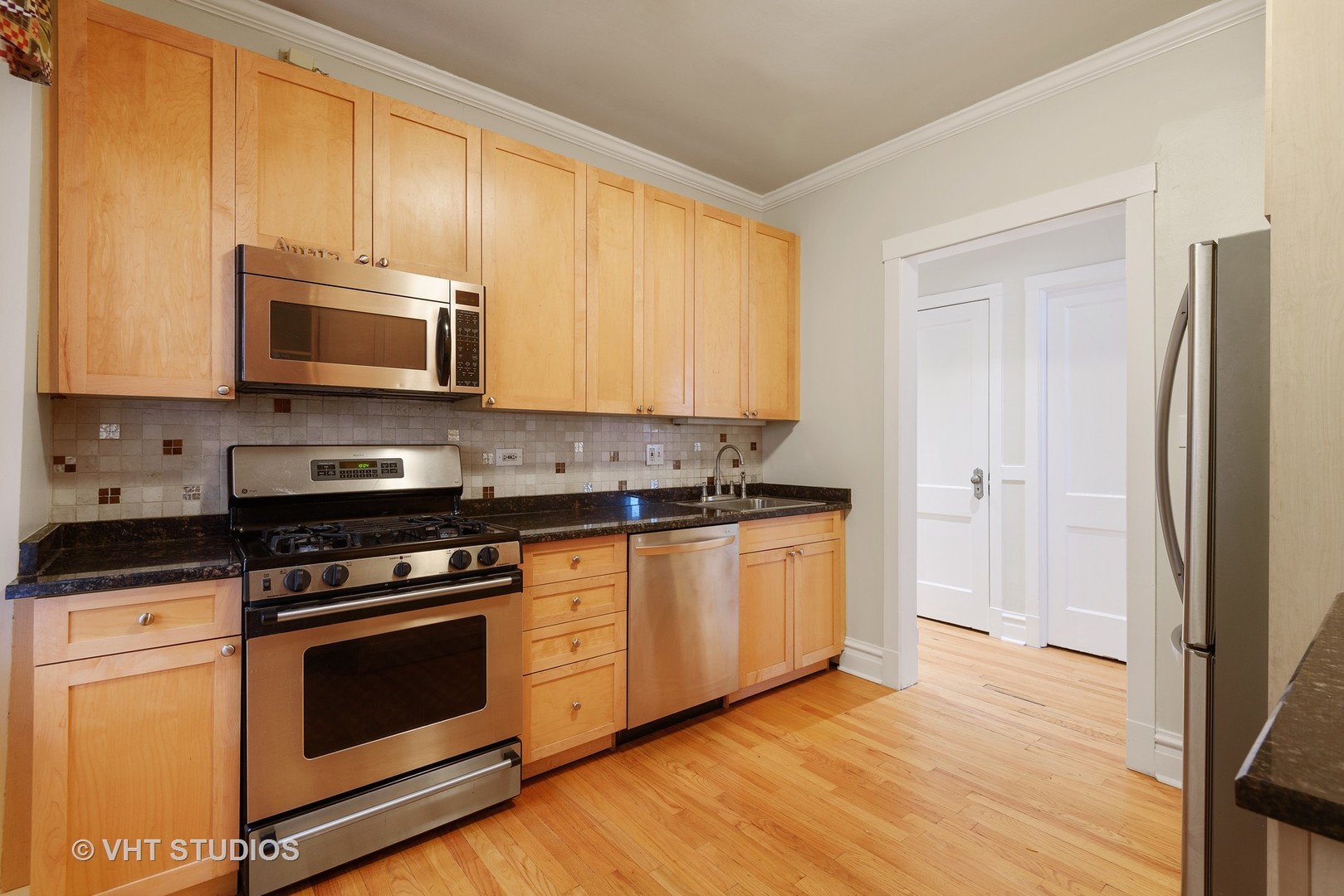 834 West Lakeside Place, Unit 2N Chicago, IL 60640 - Photo 3 of 13 a kitchen with granite countertop wooden cabinets stainless steel appliances and a window