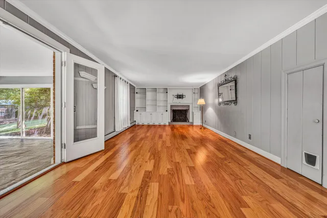 a view of empty room with wooden floor and fan