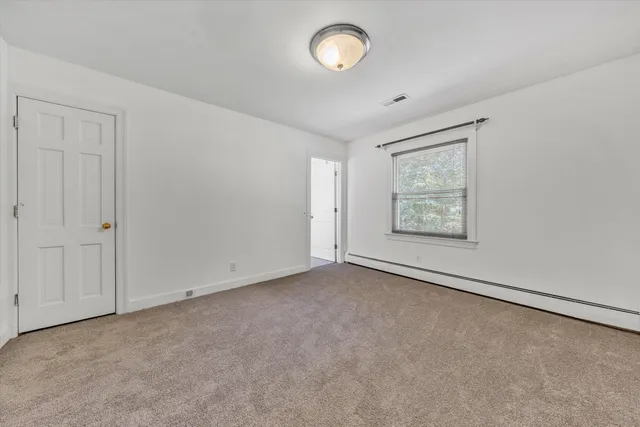 an empty room with a fan & a window