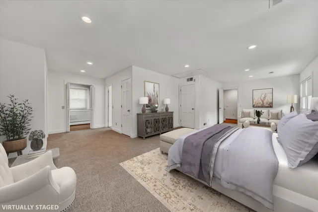 a spacious bedroom with a bed a couch and potted plant