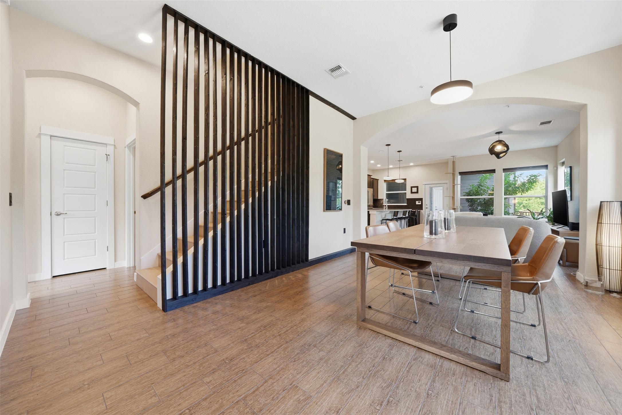3901 Vaughan Street Austin, TX 78723 - Photo 14 of 37 Open-concept living area with wood-finish flooring, a modern black slat room divider, and recessed lighting