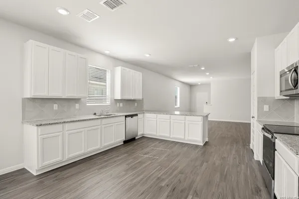 a large kitchen with a lot of counter space and wooden floor