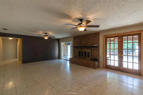 a view of a livingroom with a ceiling fan a fireplace and a large window