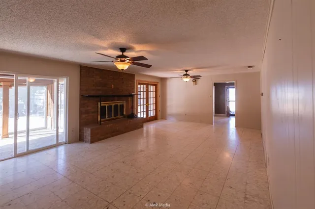 an empty room with chandelier fan and windows