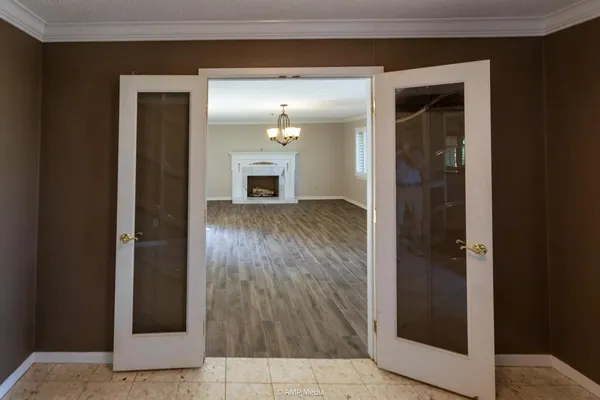 an empty room with wooden floor fireplace and windows