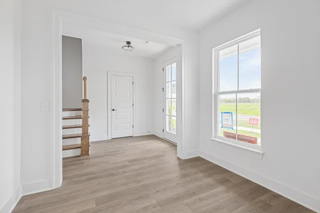 an empty room with wooden floor closet and windows