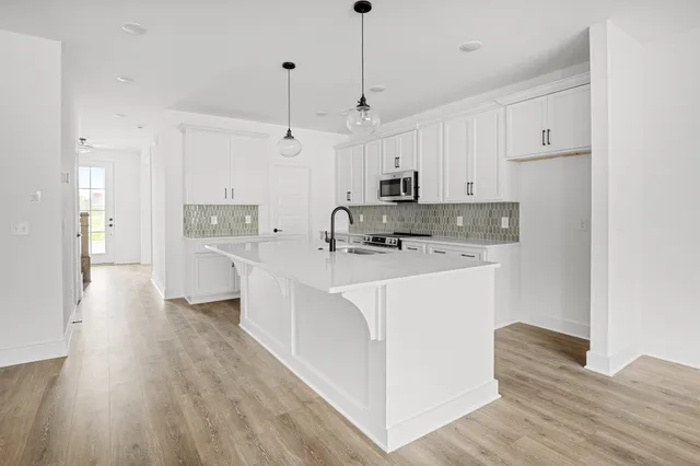 a kitchen with stainless steel appliances white cabinets a sink a stove a refrigerator and white cabinets