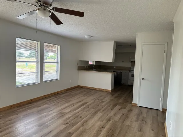a view of empty room with wooden floor and ceiling fan