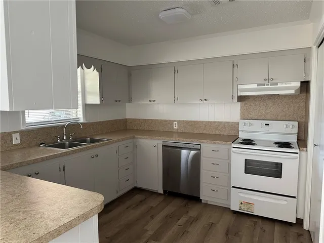 a kitchen with cabinets appliances a sink and a window