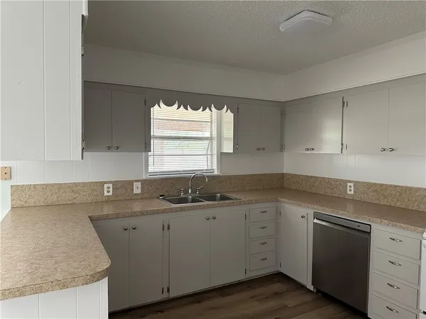 a kitchen with white cabinets appliances a sink and a window