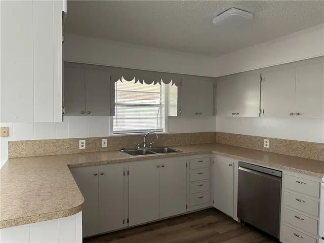 a kitchen with white cabinets appliances a sink and a window