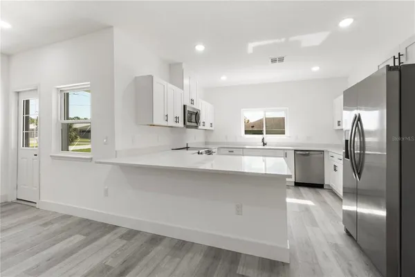 a large kitchen with stainless steel appliances a sink a window and a refrigerator
