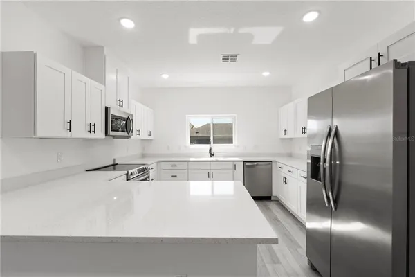 a view of a kitchen with a refrigerator a sink dishwasher with a dining table and chairs