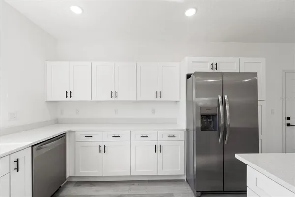 a kitchen with white cabinets and refrigerator