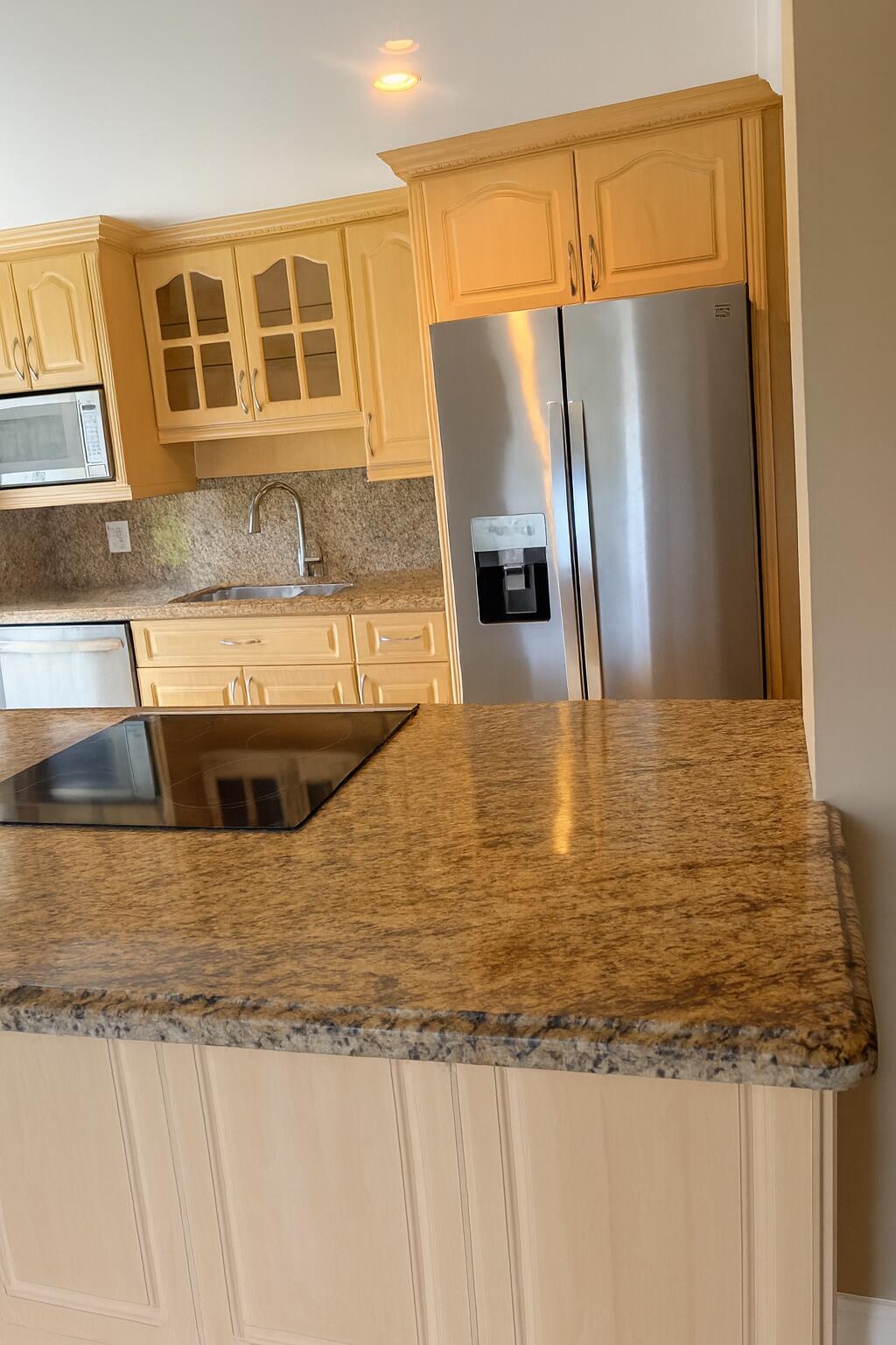 1470 South Ocean Boulevard, Unit 901 Lauderdale-by-the-Sea, FL 33062 - Photo 6 of 13 a kitchen with kitchen island a counter top and a refrigerator