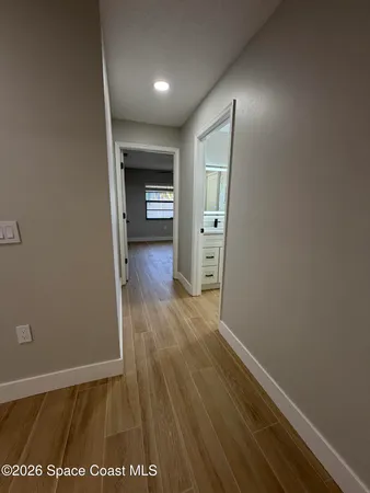 an empty room with wooden floor chandelier fan and windows