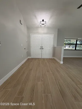 an empty room with wooden floor ceiling fan and windows