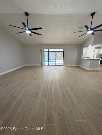 an empty room with windows and ceiling fan